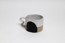 Load image into Gallery viewer, The white version of this mug is white on the top half and beige on the bottom half, with a large round black shape across both halves.
