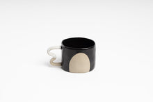 Load image into Gallery viewer, The black version of this mug is black with a white handle and has a large round beige shape.
